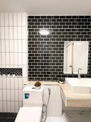 Bathroom with a countertop basin and black and white wall tiles