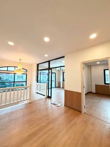 Upstairs landing with wood-look flooring, a white balustrade and black-framed sliding glass