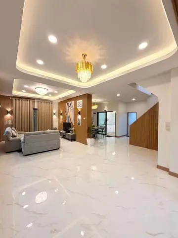 Open ground-floor hall with marble-look tiles, cove lighting and the stairs to the first floor