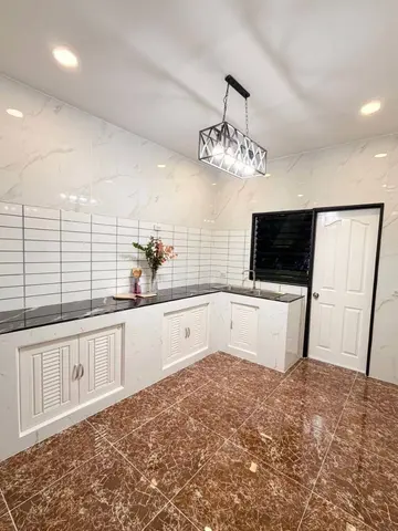 Kitchen with a worktop, base cabinets and white wall tiles. No appliances in the photo